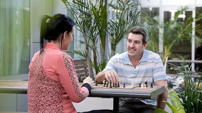 Couple playing chess at hospital courtyard